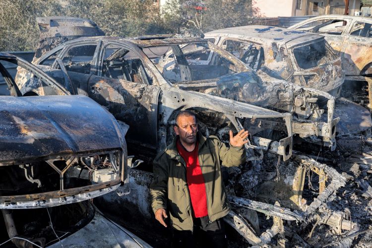 ""فلسطيني من سكان حوارة يقف وسط كومة من السيارات التي احرقها المستوطنون خلال هجومهم على القرية