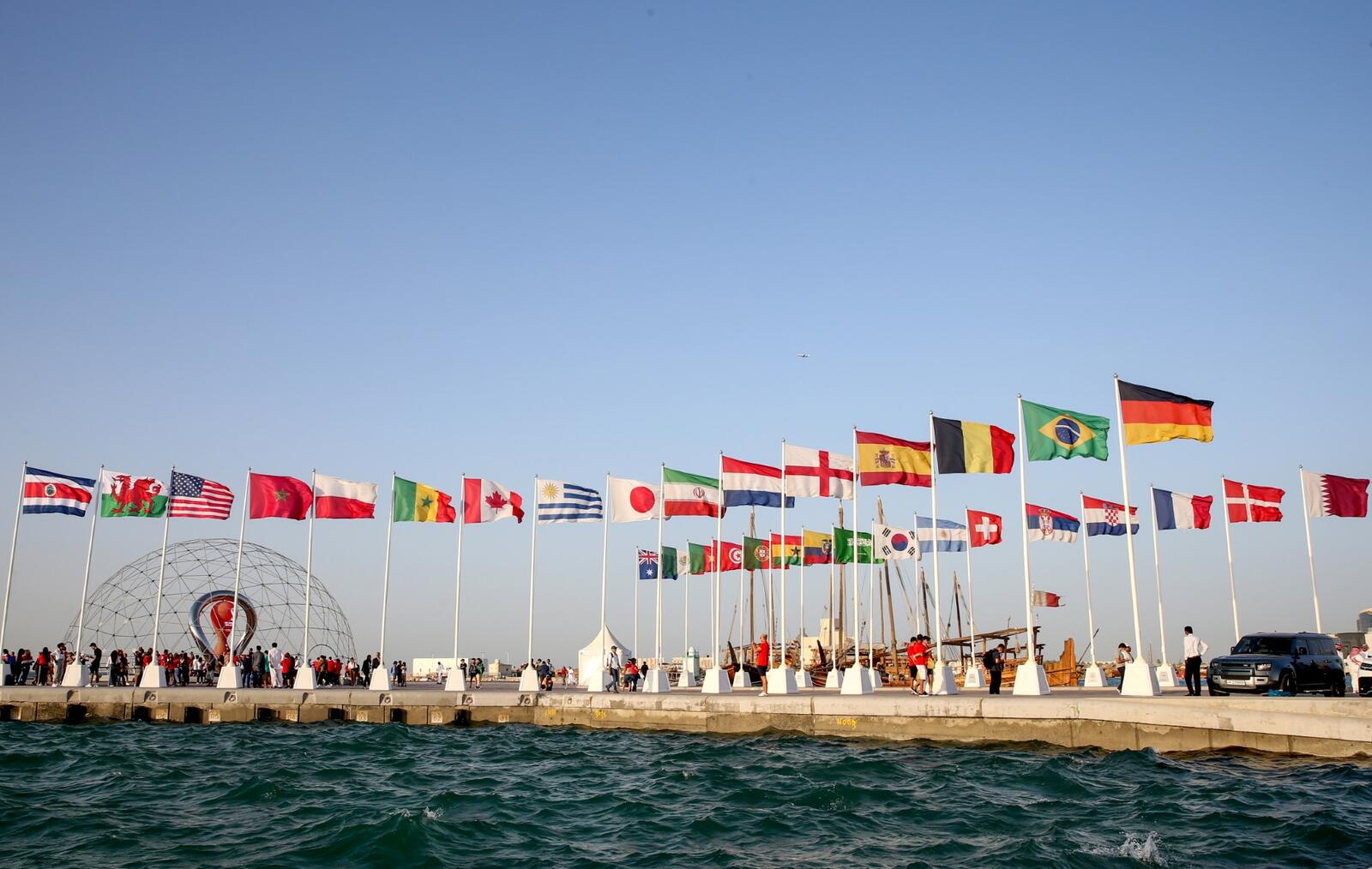 A general view shows flags of the qualified countries for the 2022 World Cup in the Qatari capital Doha during a flag-raising ceremony of the last remaining countries to qualify, on June 16, 2022. (Photo by Mustafa ABUMUNES / AFP)