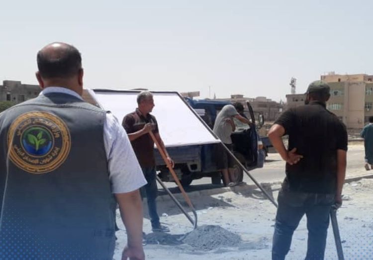 عاملون في بلدية طرابلس خلال وضعهم لافتات توضح ان مياه البحر غير صالحة للسباحة