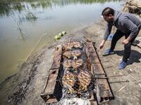 An Iraqi tourist grills fish by the marshes of the southern district of Chibayish in Dhi Qar province, about 120 kilometres northwest of the southern city of Basra, on March 29, 2019. Hussein FALEH / AFP