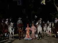 People in traditional Sevillian costumes ride horses and walk along the street during the "Feria de Abril" (April Fair) festival in Seville on May 6, 2019. CRISTINA QUICLER / AFP