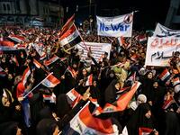 Iraqi followers of Shiite Muslim cleric Moqtada al-Sadr wave national flags and raise protest signs as they demonstrate in the capital Baghdad's central Tahrir Square late on May 24, 2019, against involvement in any conflict between Iran and the United States.  AHMAD AL-RUBAYE / AFP
