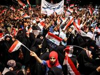 Iraqi followers of Shiite Muslim cleric Moqtada al-Sadr wave national flags and raise protest signs as they demonstrate in the capital Baghdad's central Tahrir Square late on May 24, 2019, against involvement in any conflict between Iran and the United States.  AHMAD AL-RUBAYE / AFP
