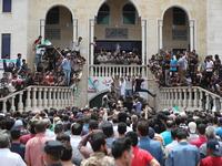 A picture taken on June 9, 2019 shows Syrians waving rebel flags and portraits of Abdel-Basset al-Sarout during the funeral of the late rebel fighter in al-Dana in Syria's jihadist-controlled Idlib region, near the border with Turkey. OMAR HAJ KADOUR / AFP