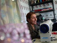 Iraq's Yazidi seamstress Shirin Ghaliyeh, 39, smiles while working at her shop in the Khonke camp for displaced persons in northwestern Iraq on June 24, 2019. SAFIN HAMED / AFP