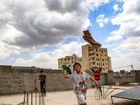 Children try to catch locusts while standing on a rooftop as they swarm over the Huthi rebel-held Yemeni capital Sanaa on July 28, 2019.  Mohammed HUWAIS / AFP