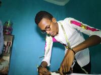 Abdishakur Abdirahman Adam, 19 years old, secondary school student and fashion designer for women and men, cuts fabrics, on November 4, 2018, in Mogadishu. Abdi HAJJI HUSSEIN / AFP