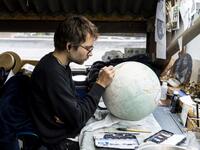 An artist applies paintwork to a globe at the Bellerby and Co Globemakers' workshop and headquarters in Stoke Newington in north London, on July 19, 2019. Niklas HALLE'N / AFP