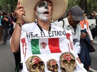 In this file photo taken on September 26, 2015 Mexican activist Julia Klug holds a fake coffin with skulls captioned "Justice, Democracy and Freedom" and a sign reading "It was the State" during a protest in Mexico City, commemorating the first anniversary of the disappearance of the Ayotzinapa students. Yuri CORTEZ / AFP