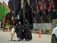 Women walk past a mourning tent erected amidst preparations ahead of the Shiite Muslim religious mourning period of Ashura, in the central Iraqi holy shrine city of Najaf on August 31, 2019.  Haidar HAMDANI / AFP