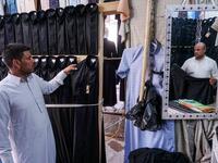 A man browses black garbs sold to Shiite Muslim pilgrims amidst preparations ahead of the Shiite religious mourning period of Ashura, in the central Iraqi holy shrine city of Najaf on August 31, 2019.  Haidar HAMDANI / AFP