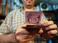 A merchant counts Syrian pound notes, bearing a portrait of the Syrian President Bashar al-Assad, at the Bzourieh market in the centre of the Syrian capital Damascus.  LOUAI BESHARA / AFP