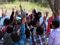 School children attend an open-air class under a tree near their unfinished school  Ahmad AL-BASHA / AFP