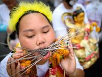 A devotee of a Chinese shrine with multiple skewers pierced through her cheeks takes part in a procession during the annual Vegetarian Festival in Phuket on October 5, 2019. Mladen ANTONOV / AFP
