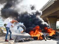 A Lebanese protester throws a tire into a fire blocking a road near Beirut-Rafic Hariri International Airport, amidst ongoing protests against dire economic conditions, on October 18, 2019. Public anger has simmered since parliament passed an austerity budget in July to help trim a ballooning deficit and flared on October 17 over new plans to tax calls on messaging applications such as WhatsApp, forcing the government to axe the unpopular proposal. AFP