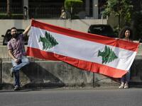 Lebanese protesters hold a national flag as they participate in forming a human chain along the coast from north to south as a symbol of unity, during ongoing anti-government demonstrations in Nahr al-Kalb north of Lebanon's capital Beirut on October 27, 2019. JOSEPH EID / AFP