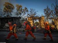 Into the inferno: Inmate firefighters walk past a burned home as they prepare to battle the wind-driven blaze in Brentwood, California which has destroyed several homes and forced schools to shut. (AFP)
