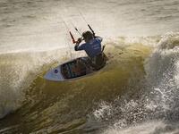 A picture taken on October 10, 2019, shows a kitesurfer riding waves at Dakhla beach in Morocco-administered Western Sahara. In the heart of disputed Western Sahara, a former garrison town has become an unlikely tourist magnet after kitesurfers discovered the windswept desert coast on the Atlantic is perfect for their sport. FADEL SENNA / AFP