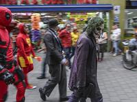 Venezuelan migrant Johnny Tales (R), who makes a living imitating the comicbook and film character "The Joker", performs followed by fellow compatriots also fancy dressed as comic and film industry characters along a street in Medellin, on October 29, 2019. JOAQUIN SARMIENTO / AFP