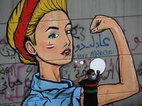 An Iraqi protester poses in front of a mural at Baghdad's Tahrir square during ongoing anti-government demonstrations on November 2, 2019. Iraqi security forces clashed with anti-government protesters in the early hours of Saturday near the capital's Tahrir Square, leaving one demonstrator dead and dozens more wounded, medical sources said. AHMAD AL-RUBAYE / AFP