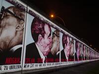 The mural painting "My God, Help Me to Survive This Deadly Love" by Russian painter Dmitri Vrubel, depicting the kiss between then Soviet leader Leonid Brezhnev (L) and East German leader Erich Honecker is projected on a stretch of the Berlin wall at the so-called East-side Gallery during the city-wide kick-off of the festival week to celebrate the 30th anniversary of the November 9,1989 fall of the Berlin Wall, in Berlin on November 4, 2019. Germany marks three decades since the fall of the Berlin Wall thi
