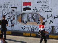 Iraqis walk past graffiti hailing Iraq's tuk-tuk drivers who have been helping protesters in Baghdad's Tahrir square, as the Iraqi capital braces for another day of protests on November 6, 2019. Arabic slogans on the wall read: "Our Tuk-tuk drivers are in the fire, they help others.. they are better than America and Iran together." The drivers of the motorised rickshaws, typically seen in poorer parts of the capital, have become the unofficial heros of the protest movement. SABAH ARAR / AFP