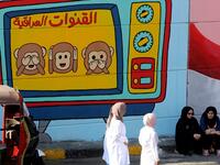 Iraqi women are pictured in front of a colourful mural in Baghdad on November 6, 2019 representing Iraqi TV channels, "that do not want to see, hear or speak about" the anti-government protests that have engulfed Iraq since early October. A mounting death toll in Baghdad and across southern Iraq coupled with renewed internet restrictions sparked fears that anti-government protests would once again trigger chaos. SABAH ARAR / AFP