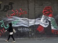 A woman walks past a graffiti drawn on the wall of a building at the al-Nour Square in the northern port city of Tripoli on November 7, 2019. An unprecedented protest movement has gripped Lebanon since October 17, demanding an overhaul of a political class that has remained largely unchanged since the end of the country's 1975-1990 civil war. In the northern city of Tripoli, where mobilisation has been relentless since the protests erupted on October 17, demonstrators took down politicians' portraits from c
