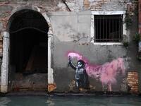 The artwork by street artist Banksy, that portrays a migrant child wearing a lifejacket and holding a neon pink flare, is pictured after an exceptional overnight "Alta Acqua" high tide water level, on November 13, 2019 in Venice. Venice was hit by the highest tide in more than 50 years late November 12, with tourists wading through flooded streets to seek shelter as a fierce wind whipped up waves in St. Mark's Square. Marco Bertorello / AFP
