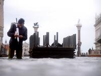 A man prepares a cigarette as he walks in the water of the flooded St. Mark's Square, on November 15, 2019 in Venice, two days after the city suffered its highest tide in 50 years. Flood-hit Venice was bracing for another exceptional high tide on November 15, as Italy declared a state of emergency for the UNESCO city where perilous deluges have caused millions of euros worth of damage. Filippo MONTEFORTE / AFP