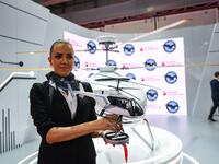 A Russian Helicopters presenter holds a model of a VRT 500 twin coaxial rotor light helicopter at a booth during the 2019 Dubai Airshow on November 18, 2019. KARIM SAHIB / AFP