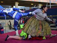 Bolivian wrestler Ana Luisa Yujra (R), aka "Jhenifer Two Faces", Lidia Flores (on the canvas), aka "Dina, The Queen of the Ring", both members of the Fighting Cholitas, and a wrestler fight at Sharks of the Ring wrestling club in El Alto, Bolivia, on November 24, 2019. After a fortnight hiatus due to anti-government protests and blockades, the Fighting Cholitas are back in the ring. The unrest was triggered by the disputed October 20 election, which Evo Morales claimed to have won and opposition groups said