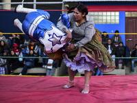 Bolivian wrestler Ana Luisa Yujra (R), aka "Jhenifer Two Faces", a member of the Fighting Cholitas, fights with a male wrestler at Sharks of the Ring wrestling club in El Alto, Bolivia, on November 24, 2019. After a fortnight hiatus due to anti-government protests and blockades, the Fighting Cholitas are back in the ring. The unrest was triggered by the disputed October 20 election, which Evo Morales claimed to have won and opposition groups said was rigged. Ronaldo SCHEMIDT / AFP