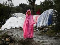 A young girl stands under the rain outside the refugee camp of Moria, on the island of Lesbos on November 26, 2019. Conditions remain difficult in the overcrowded Moria camp in Greece with winter fast approaching. The government announced on November 20it will shut down the three largest of its overcrowded migrant camps on islands facing Turkey, and replace them with new closed facilities with much larger capacity. ARIS MESSINIS / AFP
