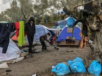 A young boy puts a jacket on his brother at the makeshift camp next to the refugee camp of Moria near the capital Mytilene in the island of Lesbos on November 29, 2019. ARIS MESSINIS / AFP