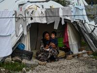 An eldery woman with her grandchild sit inside their tent at a makeshift camp next to the camp of Moria in the island of Lesbos on November 30, 2019. ARIS MESSINIS / AFP
