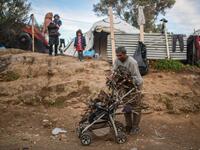 A man unloads firewoods from a baby troller at a makeshift camp next to the camp of Moria in the island of Lesbos on November 30, 2019. Conditions remain difficult in the overcrowded camp counting over 18.000 people with winter fast approaching. ARIS MESSINIS / AFP