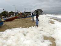 Residents play over foamy discharge, caused by pollutants, as it mixes with the surf at Marina beach in Chennai on December 1, 2019. Arun SANKAR / AFP
