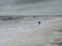 A man stands over foamy discharge, caused by pollutants, as it mixes with the surf at Marina beach in Chennai on December 1, 2019. Arun SANKAR / AFP