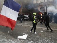 A man holding a French flag and a yellow vest walks in tear gas as protestors gesture in the background during a demonstration against the pension overhauls, in Paris, on December 5, 2019 as part of a nationwide strike. Zakaria ABDELKAFI / AFP
