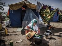 A displaced woman washes some dishes and utensils in front of her tent at a displacement camp in Beledweyne, Somalia, on December 14, 2019. The rains have inundated big areas surrounding Beledweyne area forcing thousands of people to leave their houses and look for humanitarian assistance while living in displacement camps. Due to climate change and human activities, cycles of floods and droughts have become more recurrent and completely unpredictable in Somalia exposing hundreds of thousands of people ever