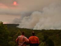 Residents watch a large bushfire as seen from Bargo, 150km southwest of Sydney, on December 19, 2019. A state of emergency was declared in Australia's most populated region on December 19 as an unprecedented heatwave fanned out-of-control bushfires, destroying homes and smothering huge areas with a toxic smoke. Peter PARKS / AFP