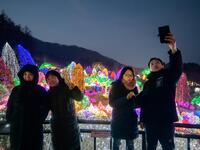 In a photo taken on January 11, 2020 visitors take a selfie as they look at an annual light display at the 'Garden on Morning Calm', near Gapyeong, east of Seoul. Ed JONES / AFP