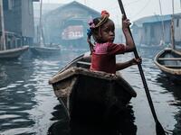 A picture taken on March 1, 2019 shows a girl steering a boat on a waterway in the Makoko waterfront community in a polluted lagoon in Lagos, Africa’s biggest megalopolis in Nigeria. The sprawling community began in the 19th century as a fishing village for immigrants who settled on the water's edge. As more arrived and land became rare, people started to move out onto the water. Over time, Makoko became a floating realm of perhaps a quarter of a million people, although the real number is anyone's guess. Y