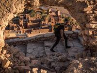 A tourist walks near the Kasbah (ancient fortress) of Ait-Ben-Haddou (background), where scenes depicting the fictional city of Yunkai from the hit HBO television series "Game of Thrones" were filmed, about 32 kilometres northwest of the city of Ouarzazate south of Morocco's High Atlas mountains on January 27, 2020. FADEL SENNA / AFP