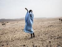 A man gestures to his family at the Touijinit Camp along the caravan route from Tichitt to Aratane in Mauritania on January 25, 2020. In the arid West African country of Mauritania, the way of life of the traditional group of hunters known as the Nemadi is slowly disappearing. JOHN WESSELS / AFP
