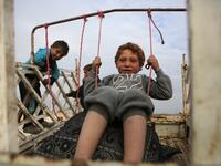 A child sits in a make-shift swing in the back of a truck in the vicinity of the northern Syrian town of Tal Abyad on February 4, 2020, where many families from the south of Aleppo province have fled to following Syrian government forces' bombardment. Bakr ALKASEM / AFP