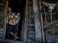 This photo taken on February 5, 2020 shows a man babysitting as his wife carries wood for the upcoming overnight ceremony by Naga tribeswomen to bless the harvest in Satpalaw Shaung village, Lahe township in Myanmar's Sagaing region. A haunting refrain pierces the night as the tribeswomen of the Gongwang Bonyo, among the most isolated people in Myanmar, dance around a campfire to bless the harvest ahead. Ye Aung THU / AFP