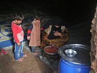 Children stand by a woman preparing food inside an underground shelter where several families of internally displaced Syrians from Aleppo and Idlib provinces are taking refuge, in the village of Taltunah about 15 kilometres northwest of Idlib in the northwestern Idlib province, on February 23, 2020. Aref TAMMAWI / AFP