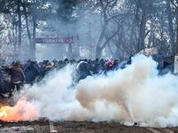 Migrants run away as Greek anti riot police officers use tears gas on the buffer zone Turkey-Greece border, at Pazarkule, in Edirne district, on February 29 , 2020. Thousands of migrants stuck on the Turkey-Greece border clashed with Greek police on February 29, 2020. Ozan KOSE / AFP